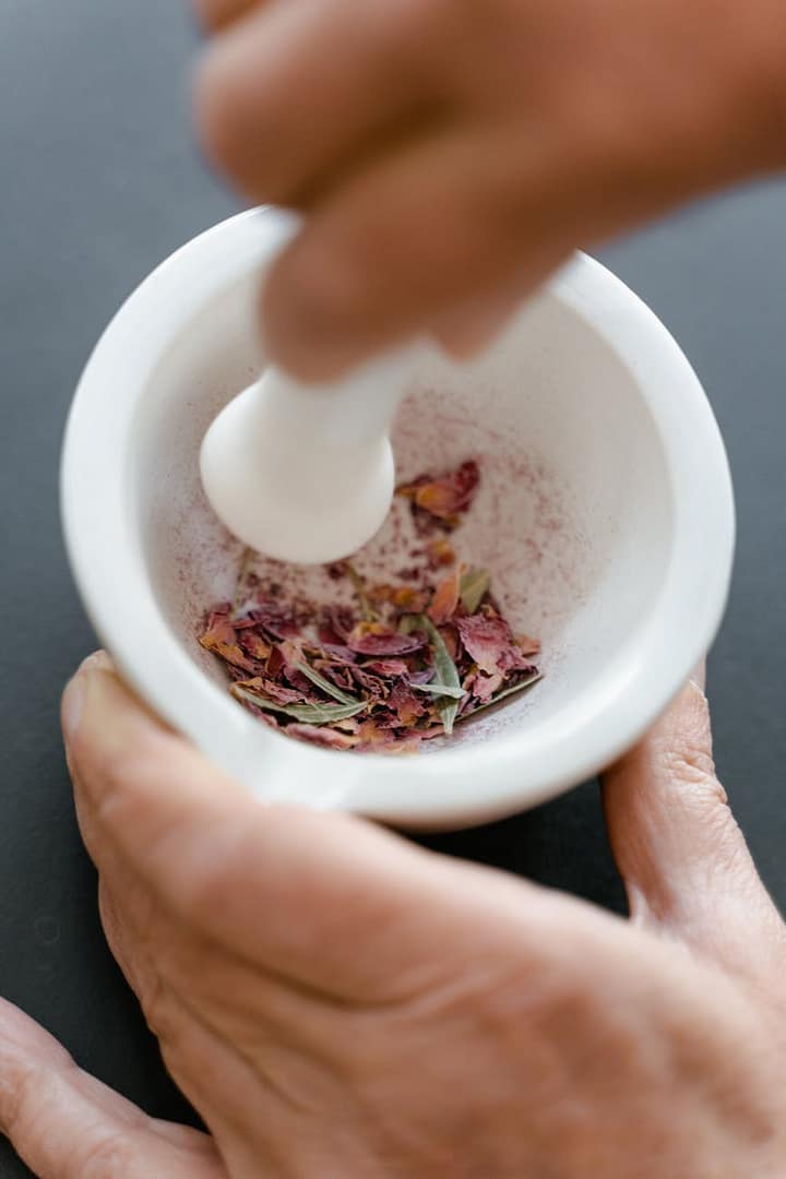 hand crushing the petals using mortar and pestle for ayurvedic skincare